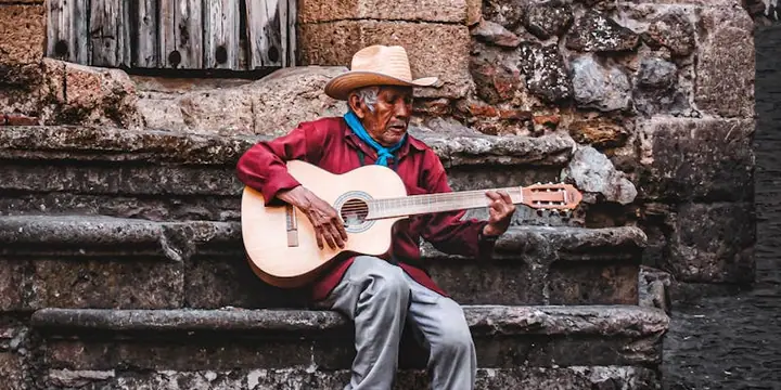 Ein Mann spielt auf einer Steintreppe sitzend Akustikgitarre